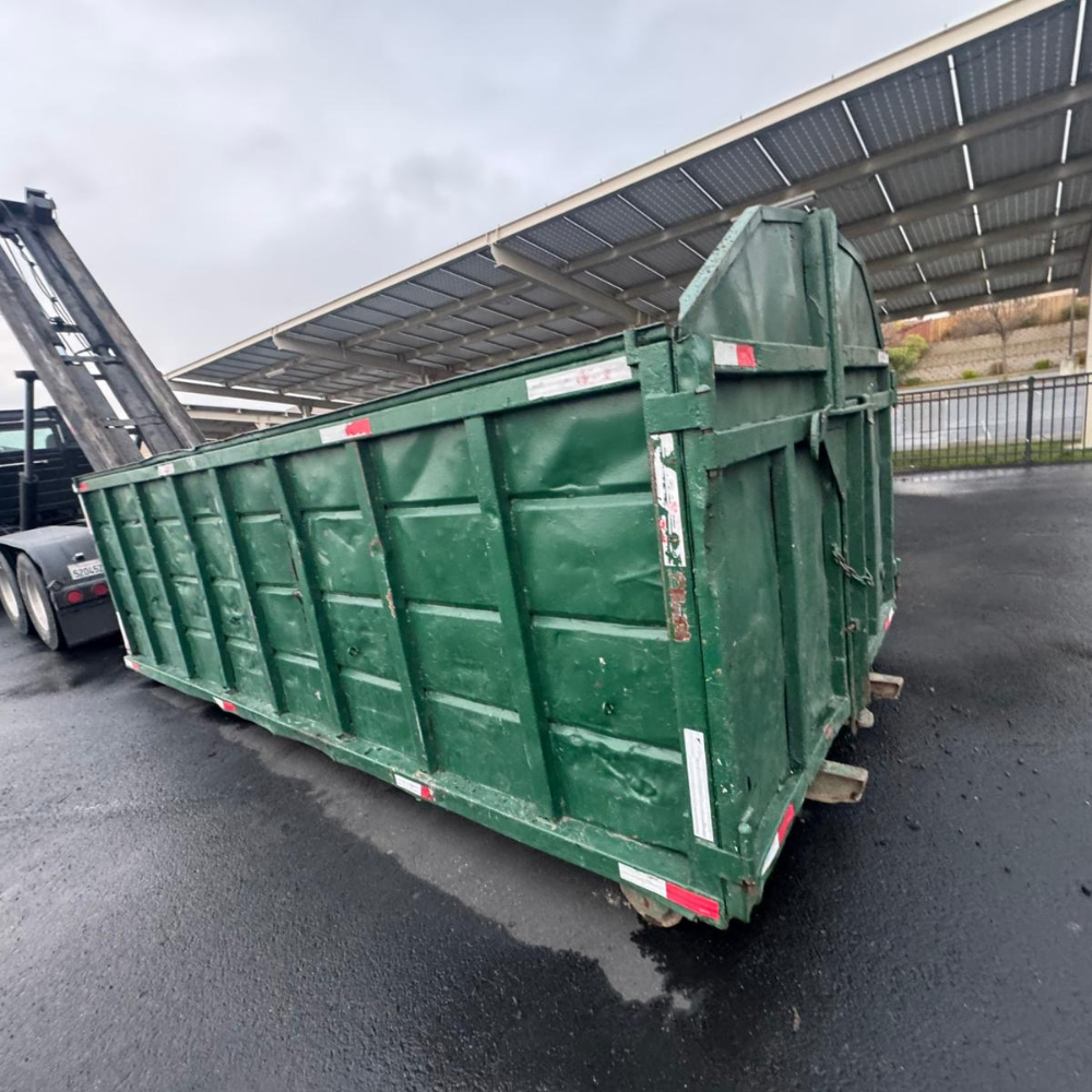 Empty green roll-off staged on a clean asphalt yard